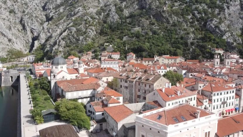 Aerial view of Kotor's Old Town, historic stone buildings, red rooftops and surrounding mountains in Montenegro.